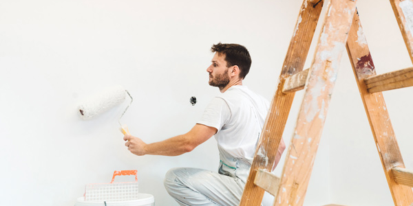 Maler streicht eine Innenwand während Renovierungsarbeiten. ERP-Software für Maler- und Handwerksbetriebe unterstützt die digitale Planung, Projektverwaltung und Administration.